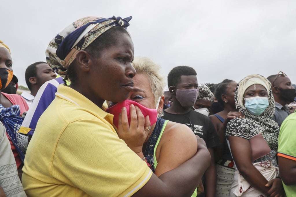A crying woman is comforted as she waits for her son to arrive in a boat of evacuees from Palma in Mozambique.