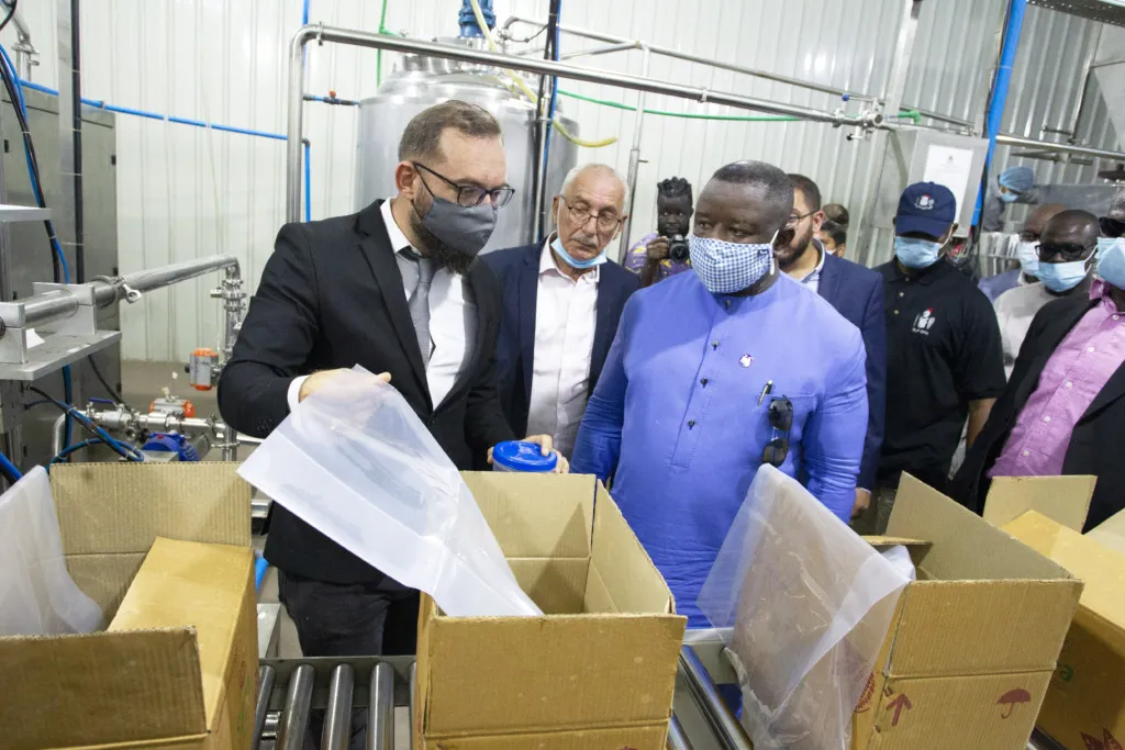 Sierra Leone's president Julius Maada Bioand Hamza Hashem inspect the finished product at Capitol Food's Factory in Kenema VIllage.