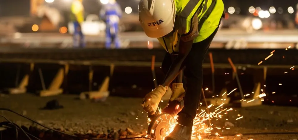 A construction worker in a hard hat operates a cutter, producing sparks, in work on a new special economic zone in Gabon.