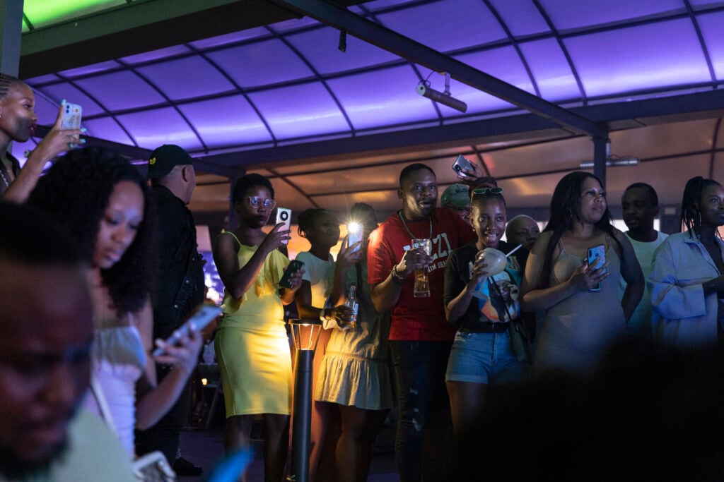 Nightclub goers holding up mobile phones.