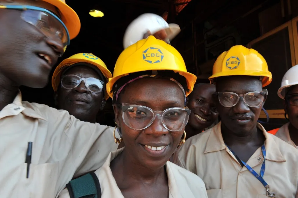 Smiling workers in protective glasses and hard hats.