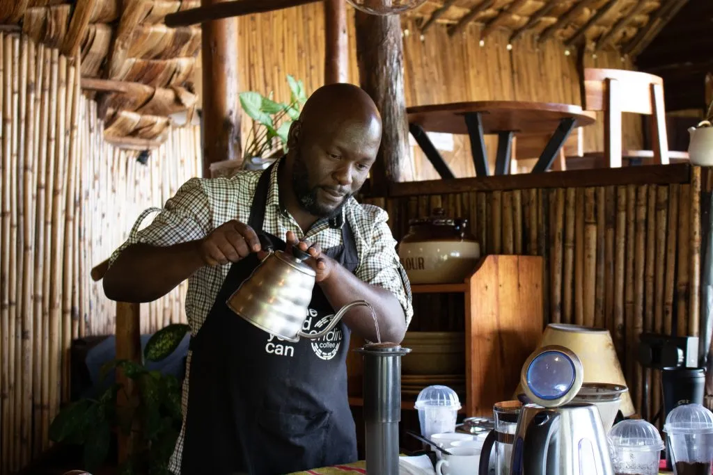 A Ugandan barista pours hot water into a filter in a coffee shop.